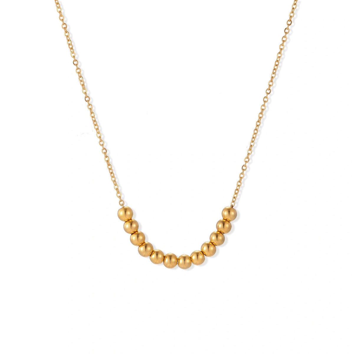 Delicate gold-plated necklace with graduated spherical beads forming gentle smile curve on beige background