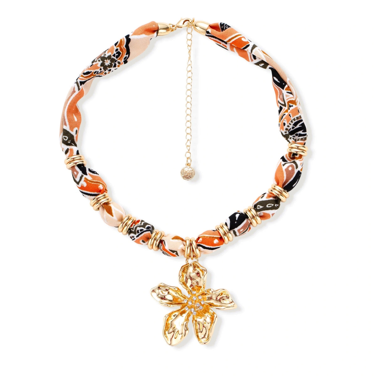 Vibrant patterned fabric necklace with gold-toned flower pendant featuring rhinestone center on white background