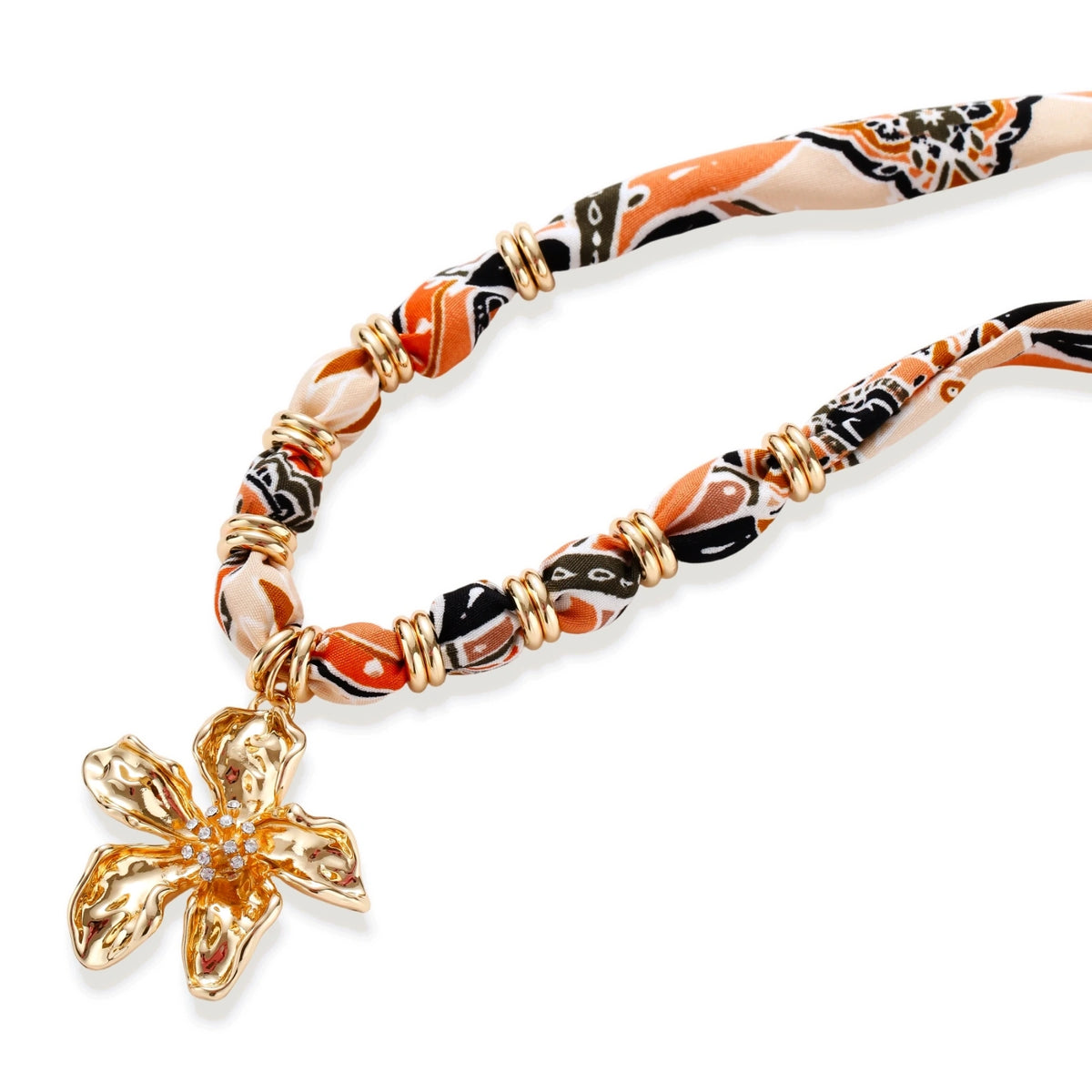 Vibrant patterned fabric necklace with gold-toned flower pendant featuring rhinestone center on white background