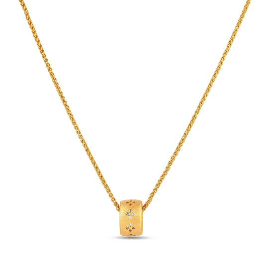 Gold-plated cylindrical ring pendant with brushed finish and scattered crystal accents on a wheat-link chain, cream background.