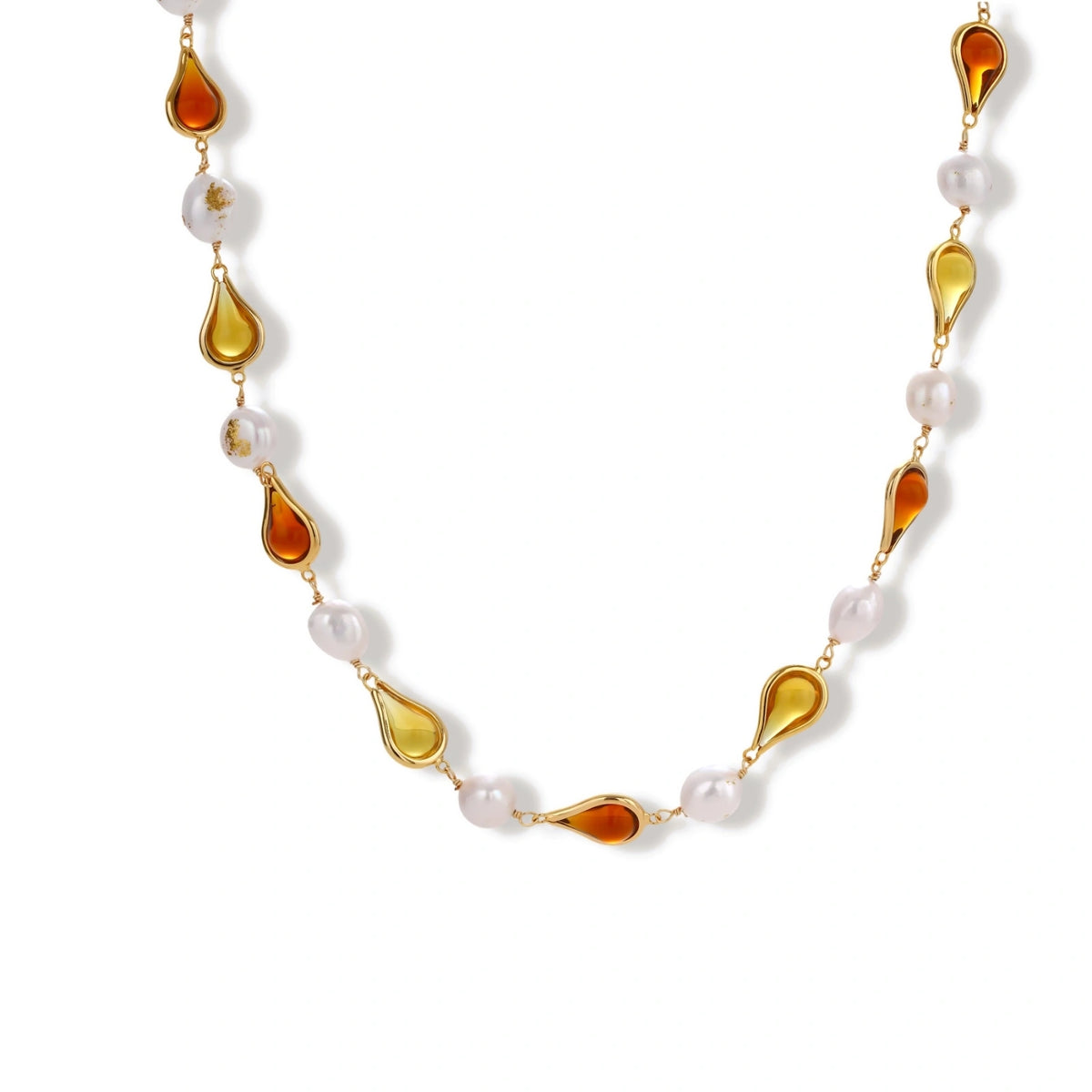 Gold-plated copper necklace with amber teardrop settings and white baroque freshwater pearls on cream background.